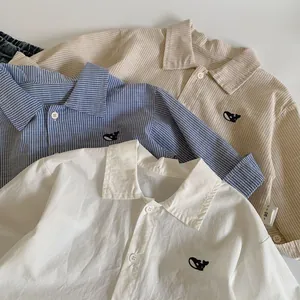 Close-up of children's cotton shirts featuring detailed whale embroidery on the chest