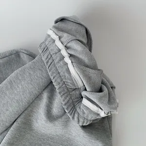 Dettaglio dei pantaloni in maglia grigi per bambini con polsino elastico e passante bianco