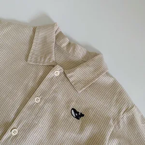 Detail of baby striped shirt featuring high-quality cotton texture and whale embroidery
