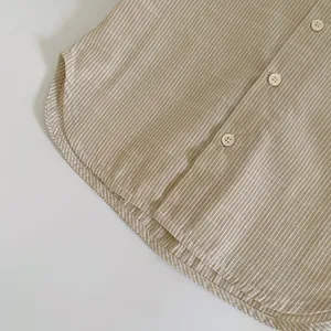 Close-up of kids striped shirt featuring beige buttons and a curved hemline detail