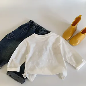 Flat lay of white long sleeve t-shirt with blue denim pants and yellow rain boots