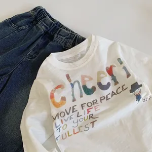 Close-up of children's white long sleeve T-shirt with colorful Cheer print and denim pants