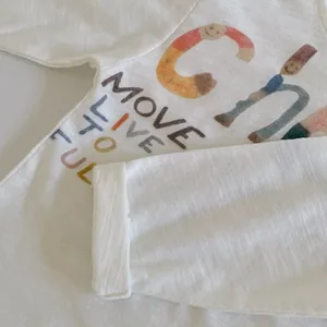 Close-up of white cotton children shirt featuring colorful artistic alphabet print