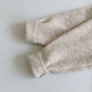 Close-up of beige knitted sweater cuff showing ribbed texture and fine knit details