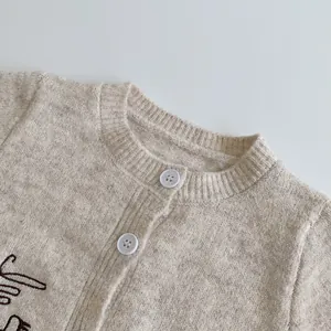 Detailed close-up of beige knit cardigan featuring delicate puppy embroidery and buttons