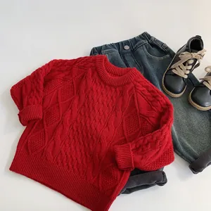 Flat lay of red cable knit sweater with dark blue jeans and black leather boots