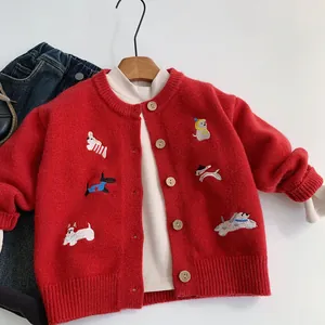 Dettaglio ravvicinato di un cardigan rosso in maglia per bambini con ricami di cani carini