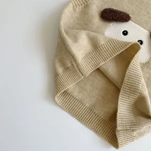 Gros plan du gilet en maille beige avec écusson chien mignon et détails de l'ourlet