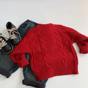 Close-up of red cable knit children's sweater with ribbed cuffs and diamond patterns