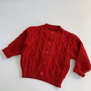 Gros plan d'un cardigan bébé en tricot torsadé rouge avec boutons et finitions côtelées