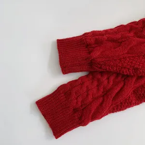 Detail of dark red cable knit pattern and ribbed cuff on a thick children sweater