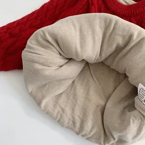 Thick red cable knit sweater with beige ribbed lining and detailed washing label
