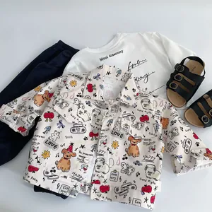 Flat lay of a toddler outfit with cartoon print jacket, white tee, and navy pants
