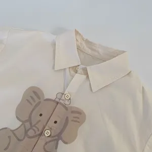 Detail of child shirt with cartoon elephant print and button collar in cream cotton