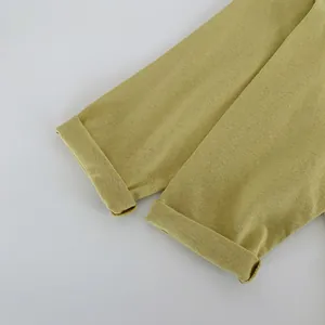 Détail macro d'une manche en coton vert moutarde avec ourlet roulé et couture fine