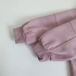 Detailed close-up of ribbed cuffs and fine stitching on a mauve kids cotton sweatshirt