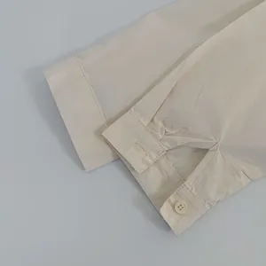 Close-up of beige cotton shirt cuff with round button and textured fabric detail