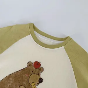 Détail des manches raglan et de l'imprimé ours sur un t-shirt enfant à manches longues