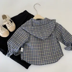 Détail de chemise à capuche à carreaux pour garçon et pantalon noir sur fond blanc