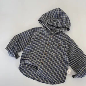 Détail d'une chemise à capuche à carreaux pour enfant avec boutons et étiquette de taille 90