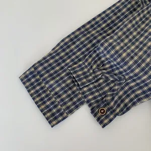 Détail du poignet d'une chemise à carreaux bleu foncé avec patte de boutonnage réglable