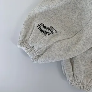 Dettaglio dei polsini in maglia di cotone grigio chiaro con stampa di lettere per bambini