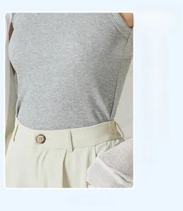Close-up of slim-fit ribbed cotton tank top paired with high-waist ivory trousers