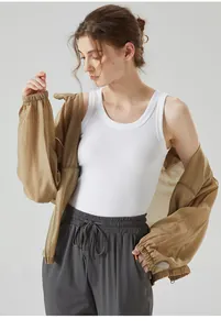 Detailed view of white ribbed tank top paired with a light brown jacket and grey joggers