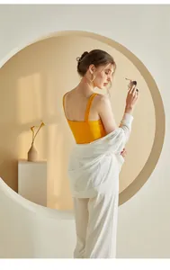 Slim fit mustard yellow knit camisole top paired with a white shirt in a modern setting