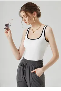 Détail du débardeur blanc moulant avec liseré noir et pantalon gris à cordon