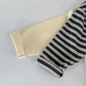 Detail of contrasting striped and solid sleeves with rolled cuffs on cotton boy's t-shirt