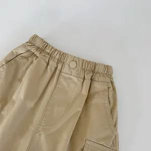 Detail showing elastic waistband and functional cargo pocket on khaki cotton kids trousers