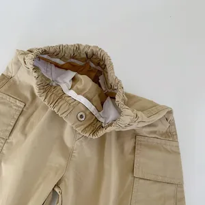 Detail of boys khaki cargo trousers showing elastic waistband with metal button and pocket
