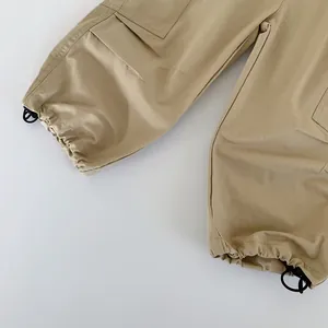 Close-up of khaki cargo pants featuring adjustable drawstring cuffs and durable cotton fabric