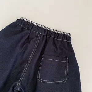 Détail d'un jean bleu foncé pour garçon avec taille élastique et surpiqûres blanches
