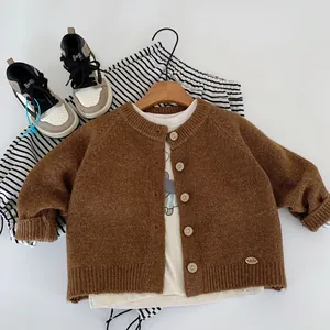 Close-up of a brown knit cardigan with wooden buttons and striped trousers set