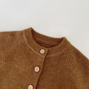 Detail of warm brown knitted cardigan featuring classic round neck and wooden buttons