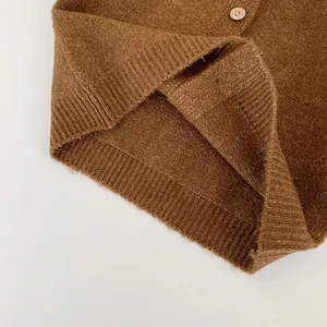 Detailed macro of the ribbed hem and wood button on this brown knit cardigan sweater