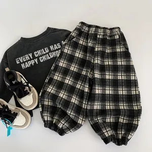 Flat lay of kids' casual outfit with grey slogan sweatshirt and plaid jogger pants
