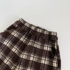 Detail of children's plaid casual pants featuring elastic waist and brown checkered pattern
