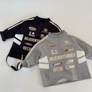 Dettaglio di felpe per bambini blu e grigie con zip e grafiche stile varsity