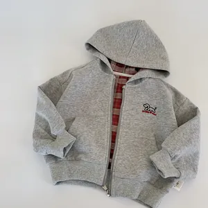 Detail of grey kids hoodie with red plaid lining and dog embroidery and size tag