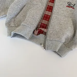 Detail of grey kids hoodie showing puppy embroidery and red plaid lining inside