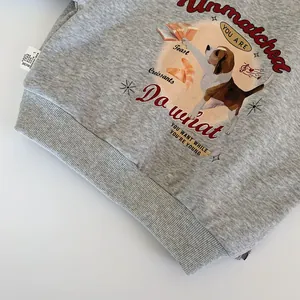 Close-up of gray knitted hoodie fabric featuring dog illustrations and side wash label