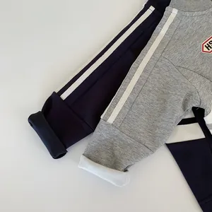 Dettaglio dei pantaloni sportivi per bambini con strisce laterali e polsini a coste blu e grigi