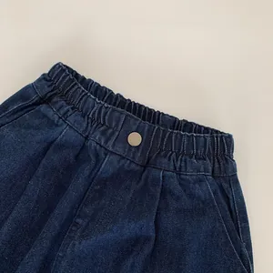 Détail de la taille élastique et bouton métallique sur un jean en denim bleu pour enfant