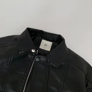 Close-up of black faux leather jacket collar with size 90 label and metallic zipper