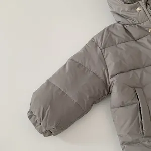 Detailansicht der gesteppten taupefarbenen Kinderdaunenjacke mit silbernen Druckknöpfen
