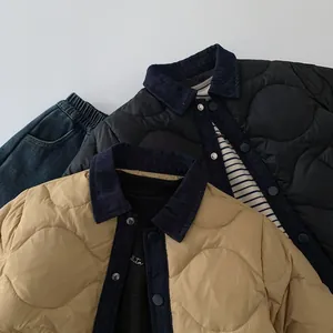 Close-up of quilted kids jacket featuring denim collar detail and metal button closure