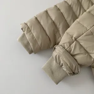 Detail of windproof ribbed cuffs on kids' beige down jacket with horizontal quilting